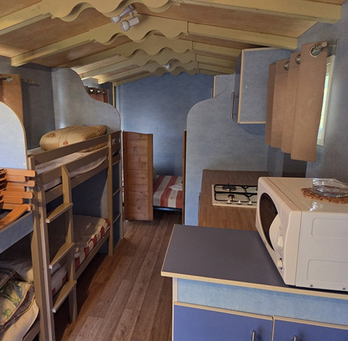 Location roulotte, hébergement insolite dans la Drôme : kitchenette équipée, chambre et coin repas
